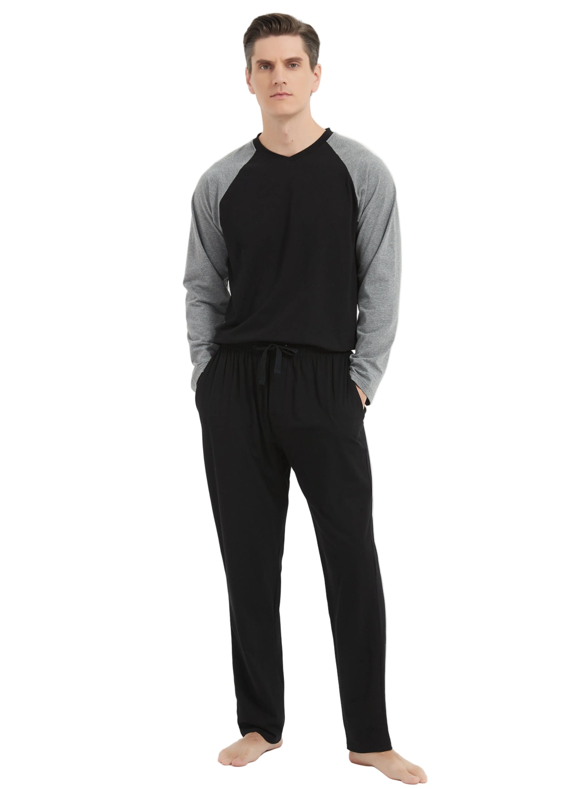 A man modeling a two-piece loungewear set consisting of a black and gray raglan long-sleeve shirt and black drawstring sweatpants, standing against a plain white studio background.