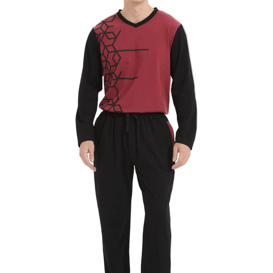 A man modeling a two-piece pajama set consisting of a long-sleeve knit top in burgundy and black with a black geometric pattern, paired with black pajama pants, against a plain white studio background.