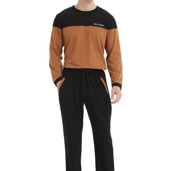 A man modeling a two-tone long-sleeve top and matching pants set. The top is color-blocked with black shoulders and sleeves and a warm brown body, featuring a small white logo on the chest.