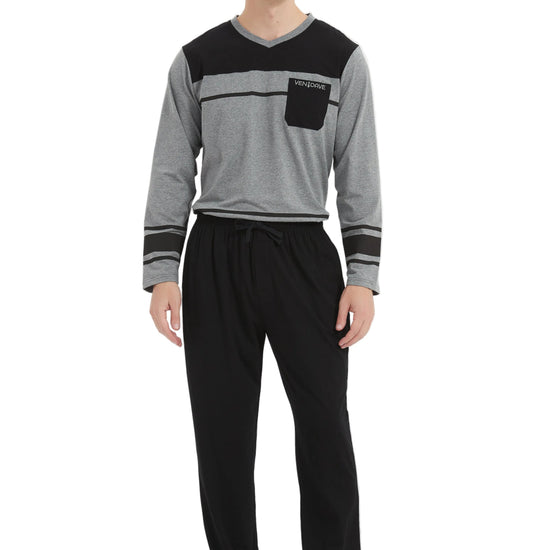A man modeling a two-piece loungewear set consisting of a gray and black long-sleeve shirt with a chest pocket, paired with black pants, against a plain white studio background.