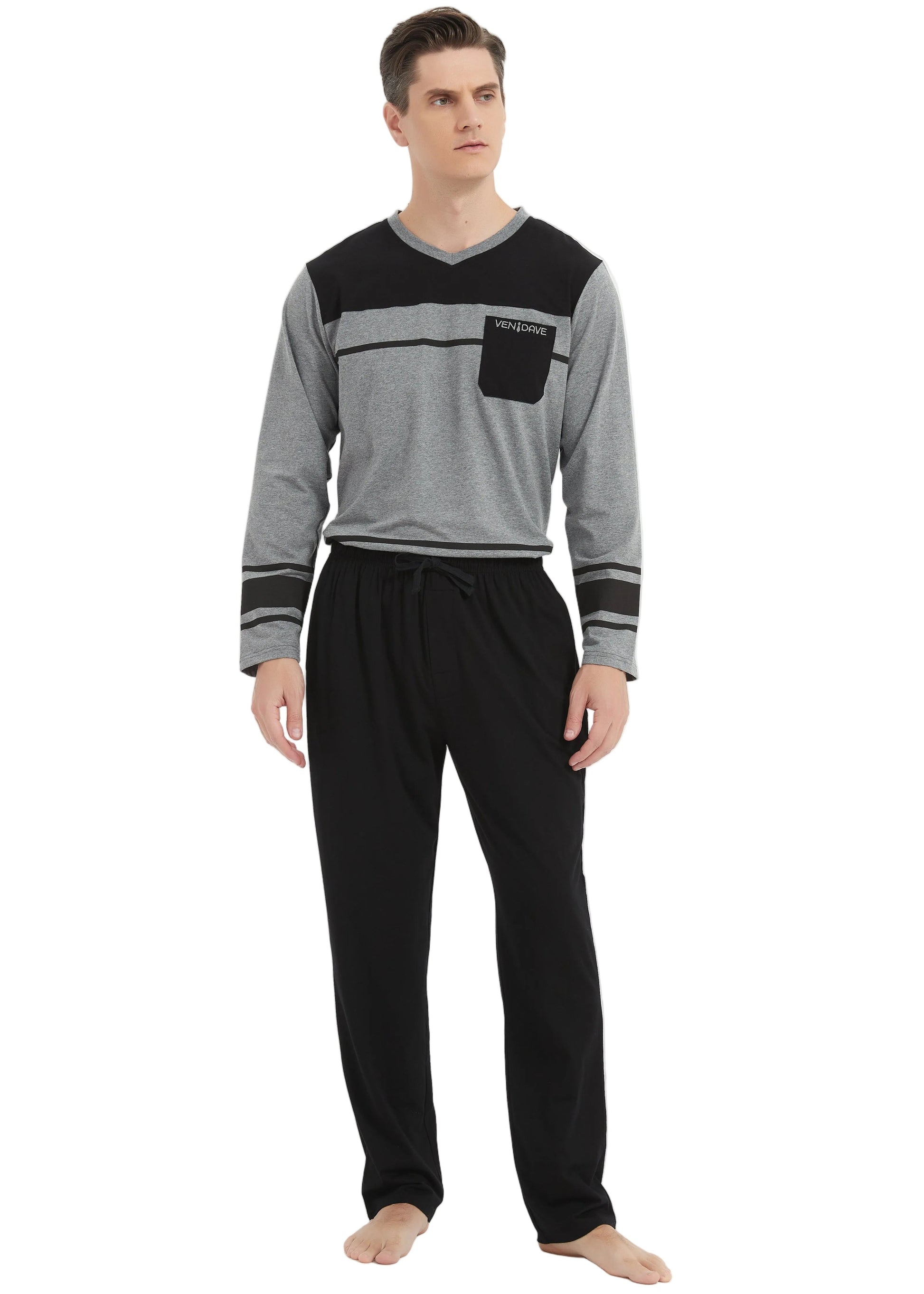 A man modeling a two-piece loungewear set consisting of a gray and black long-sleeve shirt with a chest pocket, paired with black pants, against a plain white studio background.