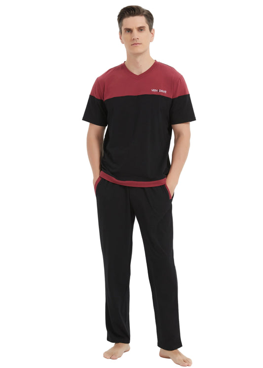 A man wearing a two-tone short-sleeve sleep set consisting of a black and maroon V-neck t-shirt with a small white logo on the chest, and matching black trousers, standing against a light gray studio background.
