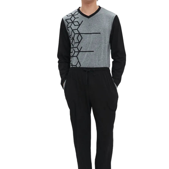 A man modeling a two-piece loungewear set consisting of a gray and black long-sleeve knit top with a geometric pattern, paired with black drawstring sweatpants, shot against a plain white studio background.