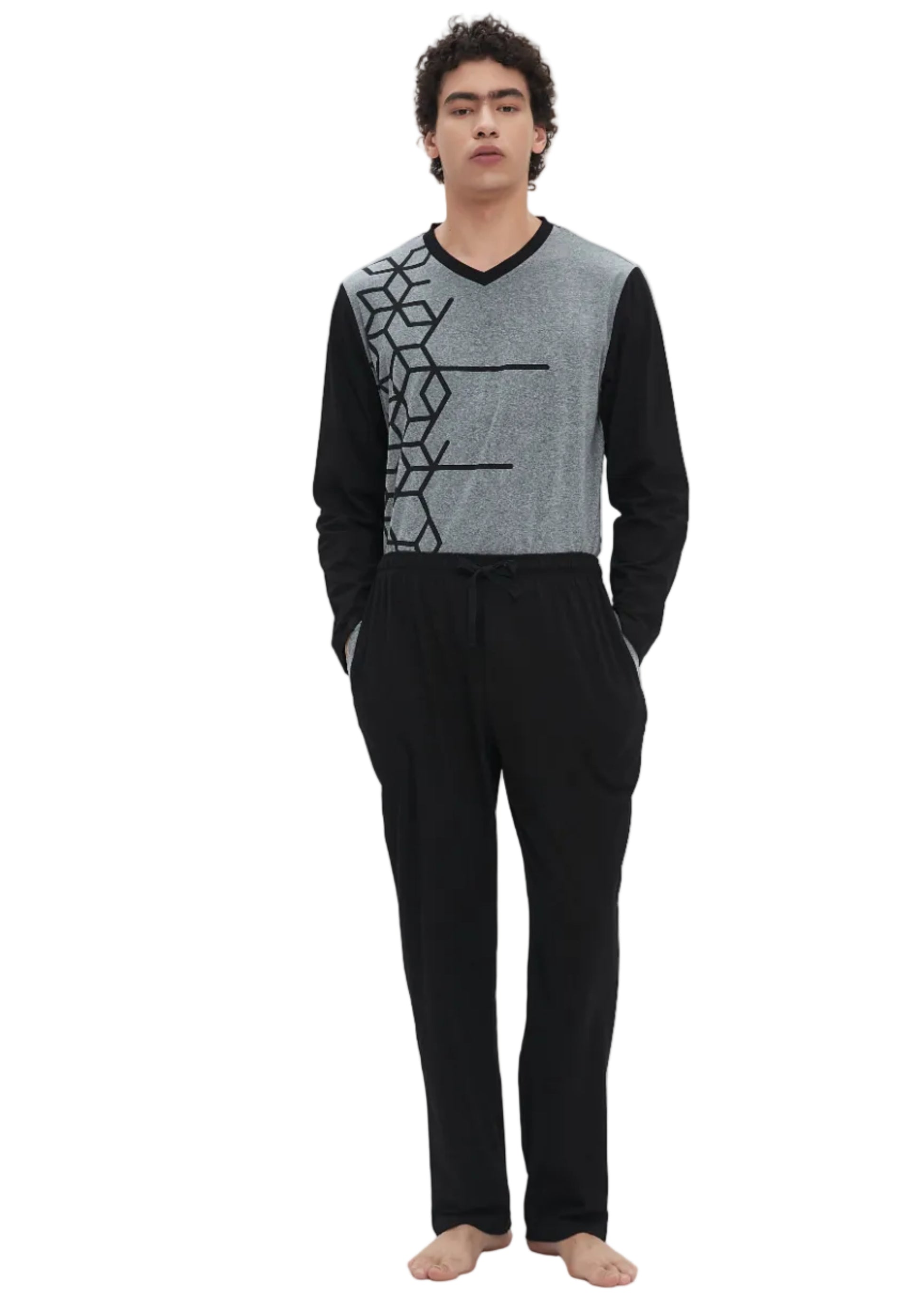 A man modeling a two-piece loungewear set consisting of a gray and black long-sleeve knit top with a geometric pattern, paired with black drawstring sweatpants, shot against a plain white studio background.