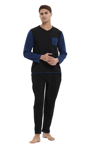 A man modeling a two-piece pajama set consisting of a long-sleeve top with a black body and navy blue sleeves, paired with black pants, against a plain white studio background.