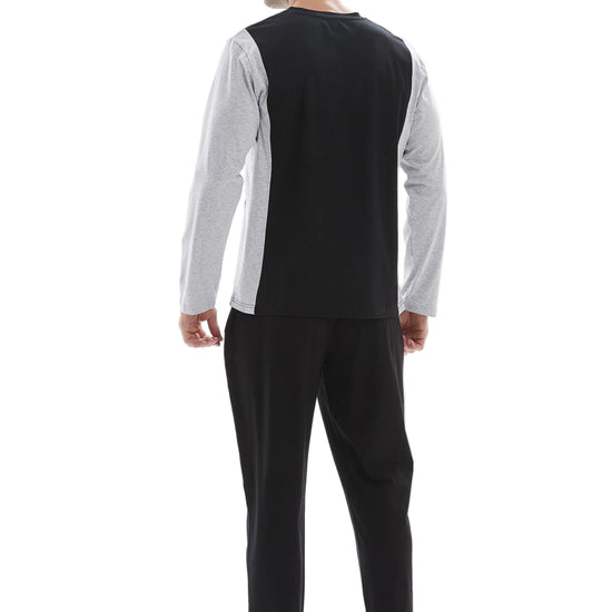 A man wearing a two-piece pajama set, viewed from the back. The set features a black and white color-blocked long-sleeve top and solid black pants, shown against a plain white studio background.