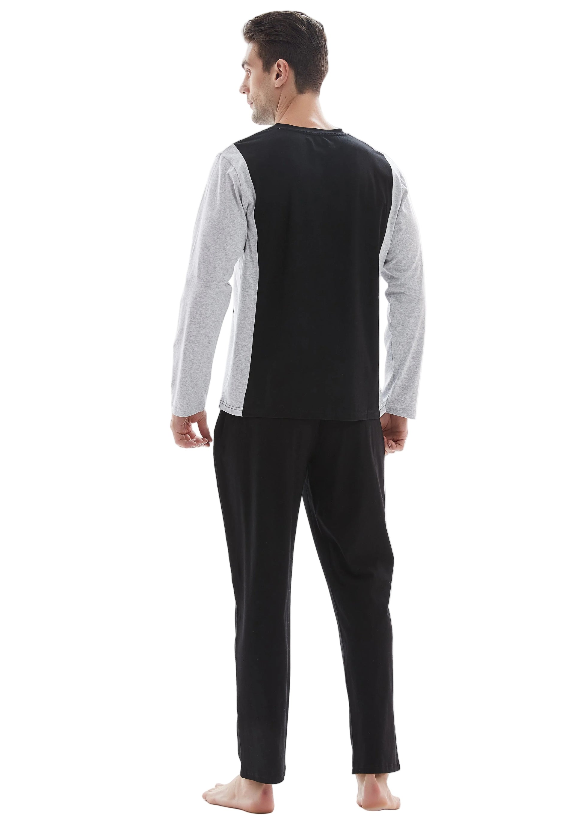 A man wearing a two-piece pajama set, viewed from the back. The set features a black and white color-blocked long-sleeve top and solid black pants, shown against a plain white studio background.