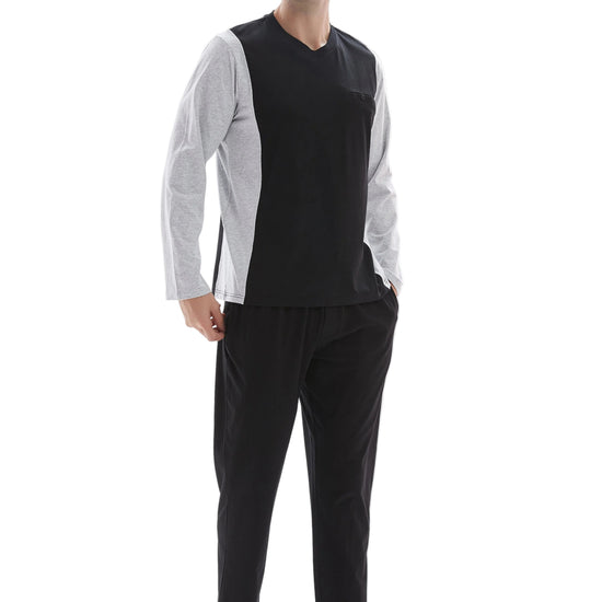 A man modeling a two-piece loungewear set consisting of a black and white color-blocked long-sleeve shirt and black pants, shot against a plain white background.