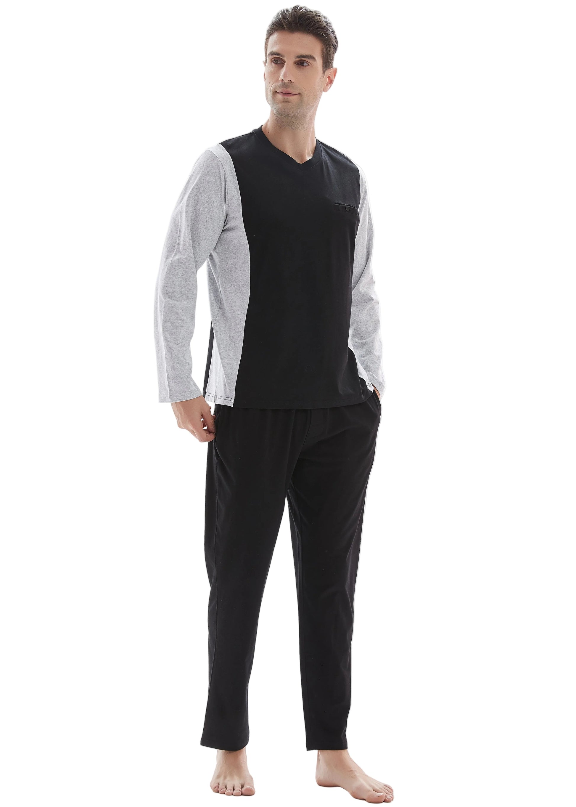 A man modeling a two-piece loungewear set consisting of a black and white color-blocked long-sleeve shirt and black pants, shot against a plain white background.