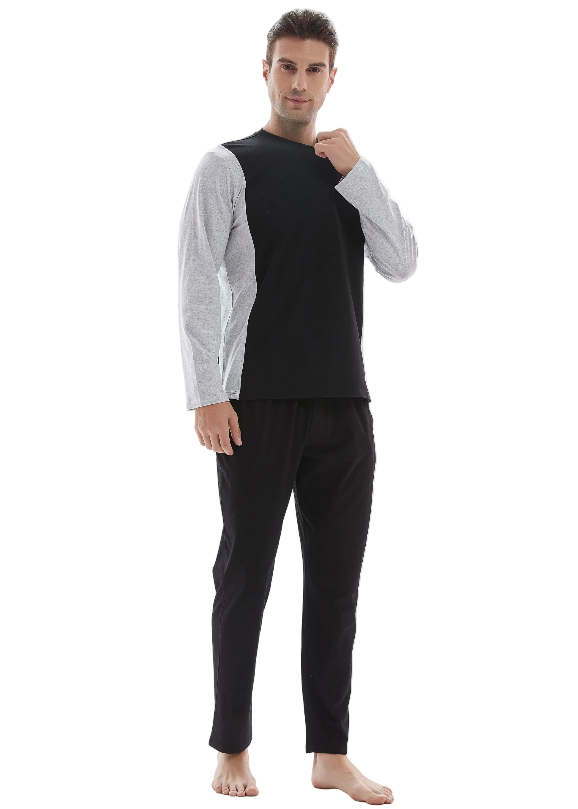 A man modeling a two-piece loungewear set consisting of a black sleeveless top over a light gray long-sleeve shirt and black pants, shot against a plain white studio background.