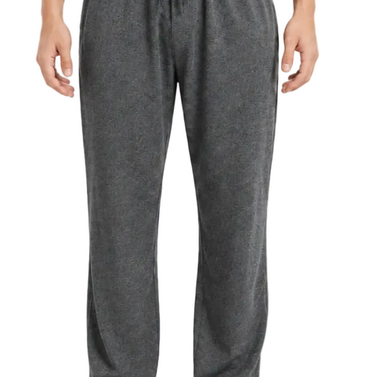 A person modeling dark gray heather lounge pants against a plain light gray studio background.