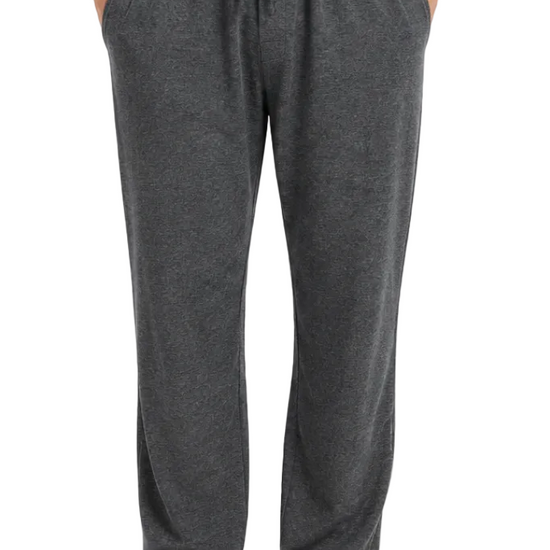 A person wearing dark gray heather lounge pants with an elastic drawstring waistband and side pockets, standing barefoot against a light gray studio background.