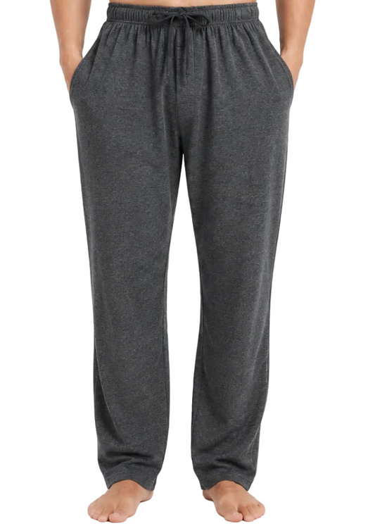 A person wearing dark gray heather lounge pants with an elastic drawstring waistband and side pockets, standing barefoot against a light gray studio background.